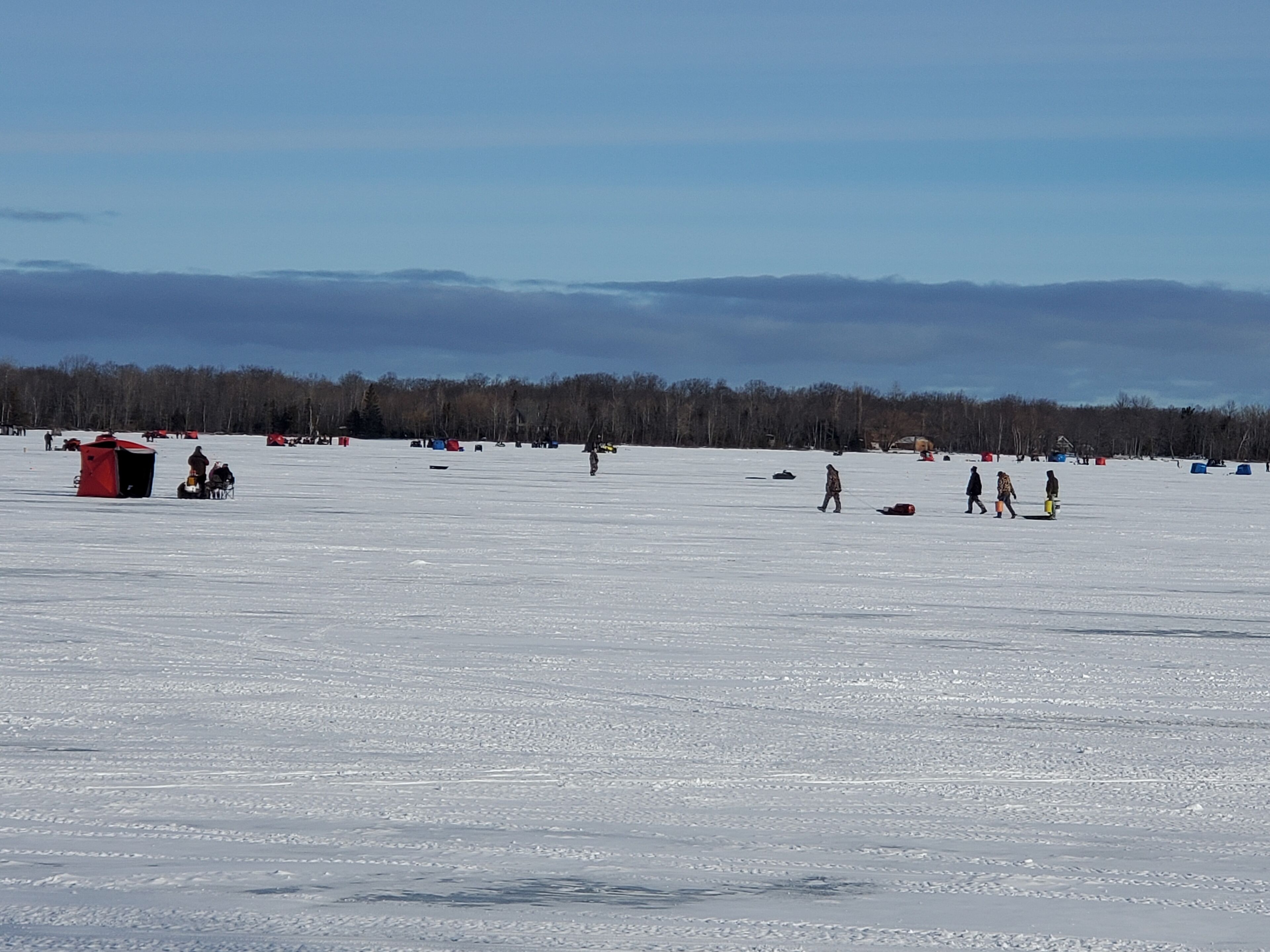 A vast, open snowy field with a few tents and people scattered around.