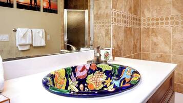 A bathroom with a colorful ceramic sink, a mirror, and a towel rack with towels.