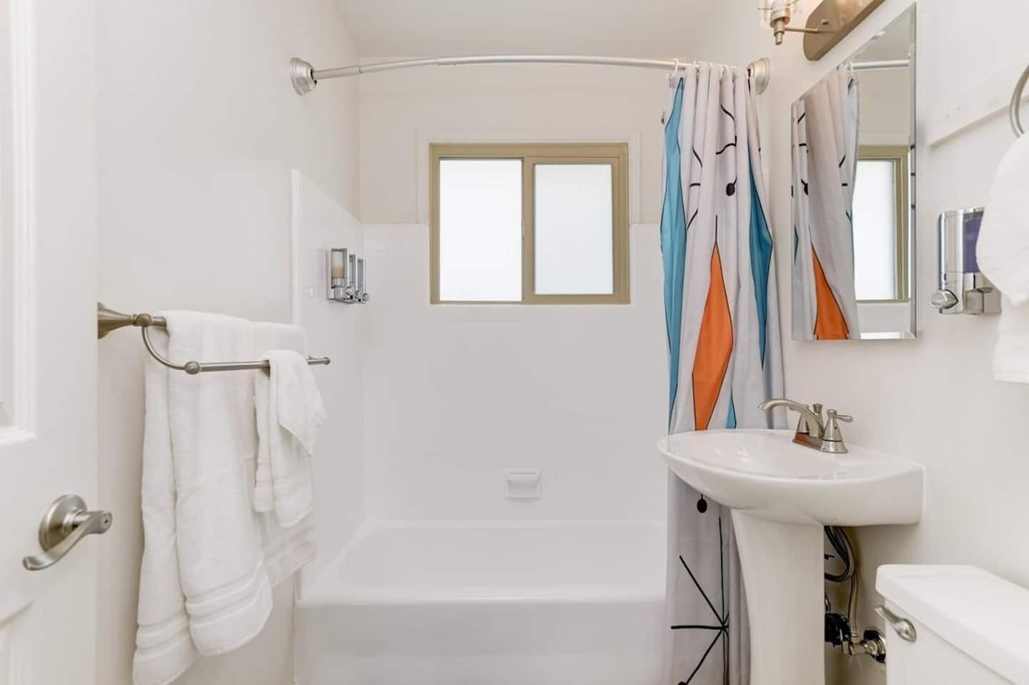 A modern bathroom with a bathtub, a white sink, and a shower curtain.
