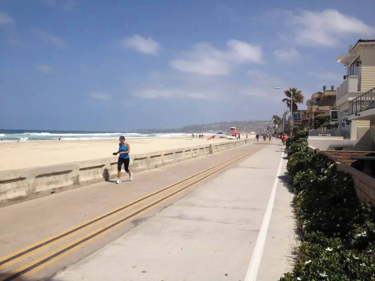 Eine Küstenstraße mit Fußweg entlang eines Strandes.