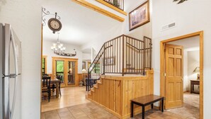 Una cocina amplia con una isla de madera, un comedor con mesa y sillas, y una escalera que conduce a un nivel superior.