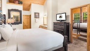 Un dormitorio con cama, cómoda, televisor y vista al exterior a través de una ventana.