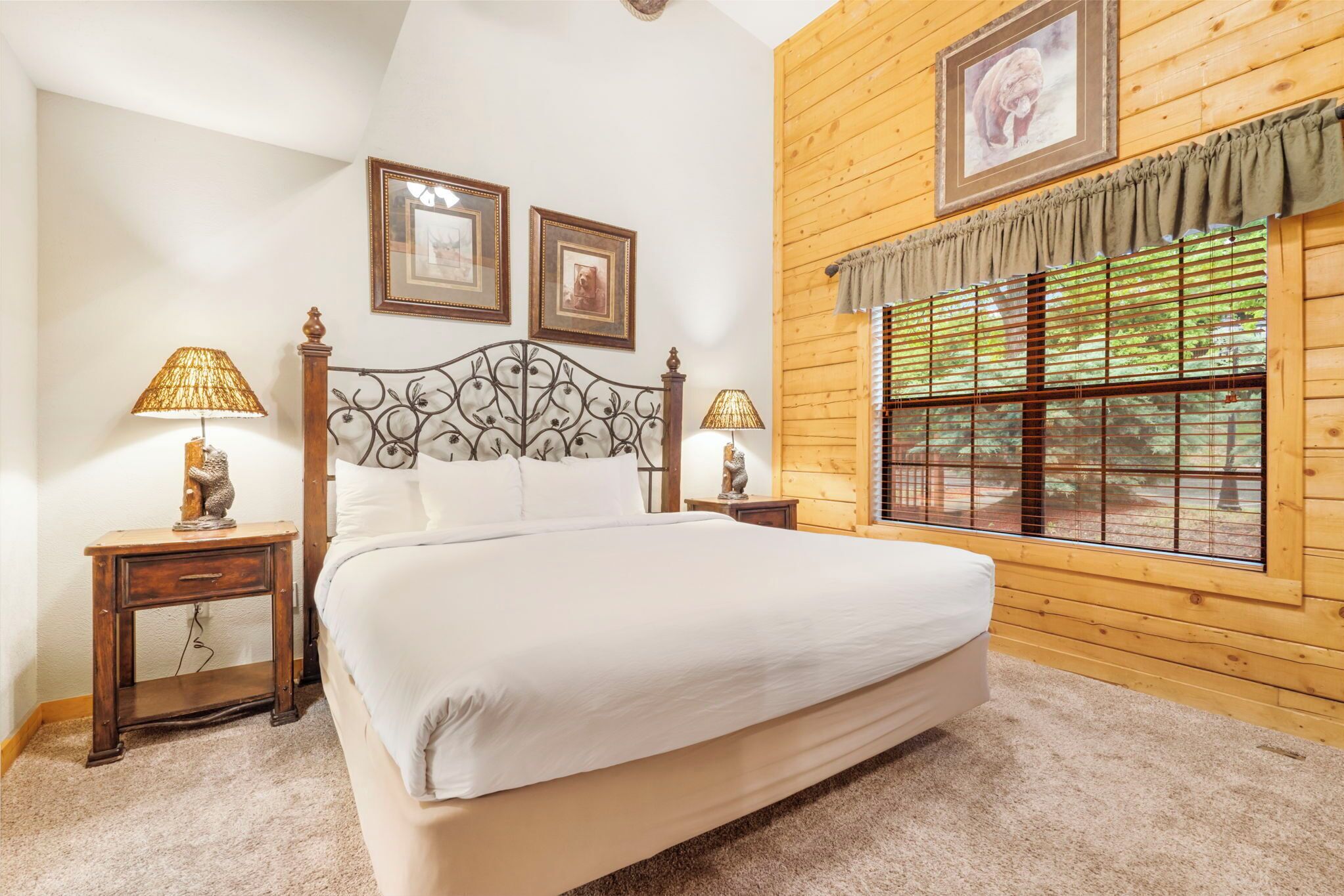 A bedroom with a large bed, wooden walls, and a window with blinds.