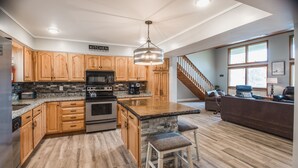 Una cocina moderna con armarios de madera, encimera de granito y una isla central con taburetes de bar.