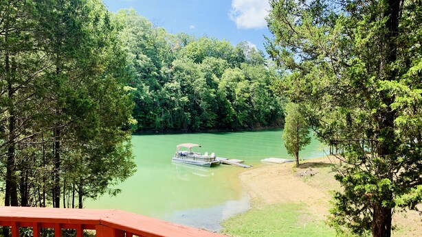 Un barco amarrado a la orilla del río, con cubierta y barandilla de madera al frente.