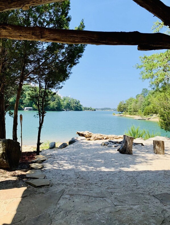 Une plage de sable offrant une vue dégagée sur un lac, entourée d’arbres et d’une structure en bois.
