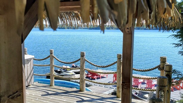 A wooden deck with a rope barrier, leading to a water body. - The Cozy Canadian Lake House (Dysart et al,)