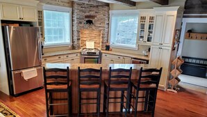 A modern kitchen with a central island, stainless steel appliances, and a stone accent wall. - The Cozy Canadian Lake House (Dysart et al,)