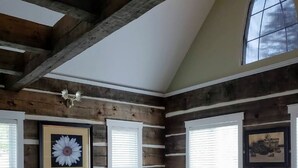 A bedroom with a wooden bed, large windows, and a sloped ceiling. - The Cozy Canadian Lake House (Dysart et al,)