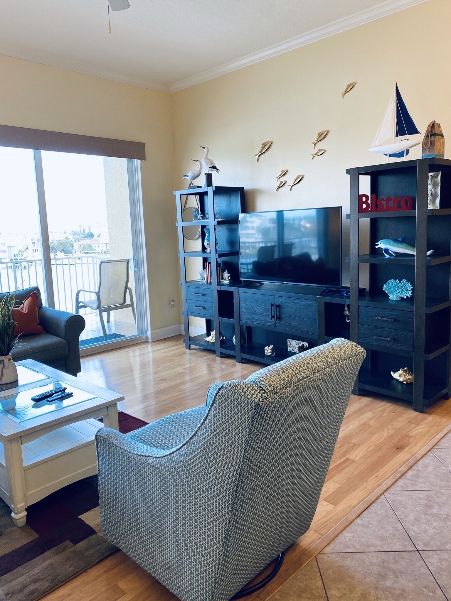Un salon comprenant un canapé, une table basse, un téléviseur et une bibliothèque agrémentée d’objets décoratifs.
