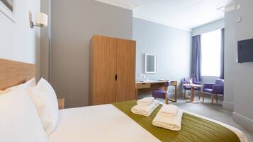 Una habitación de hotel con cama, escritorio, silla y armario.
