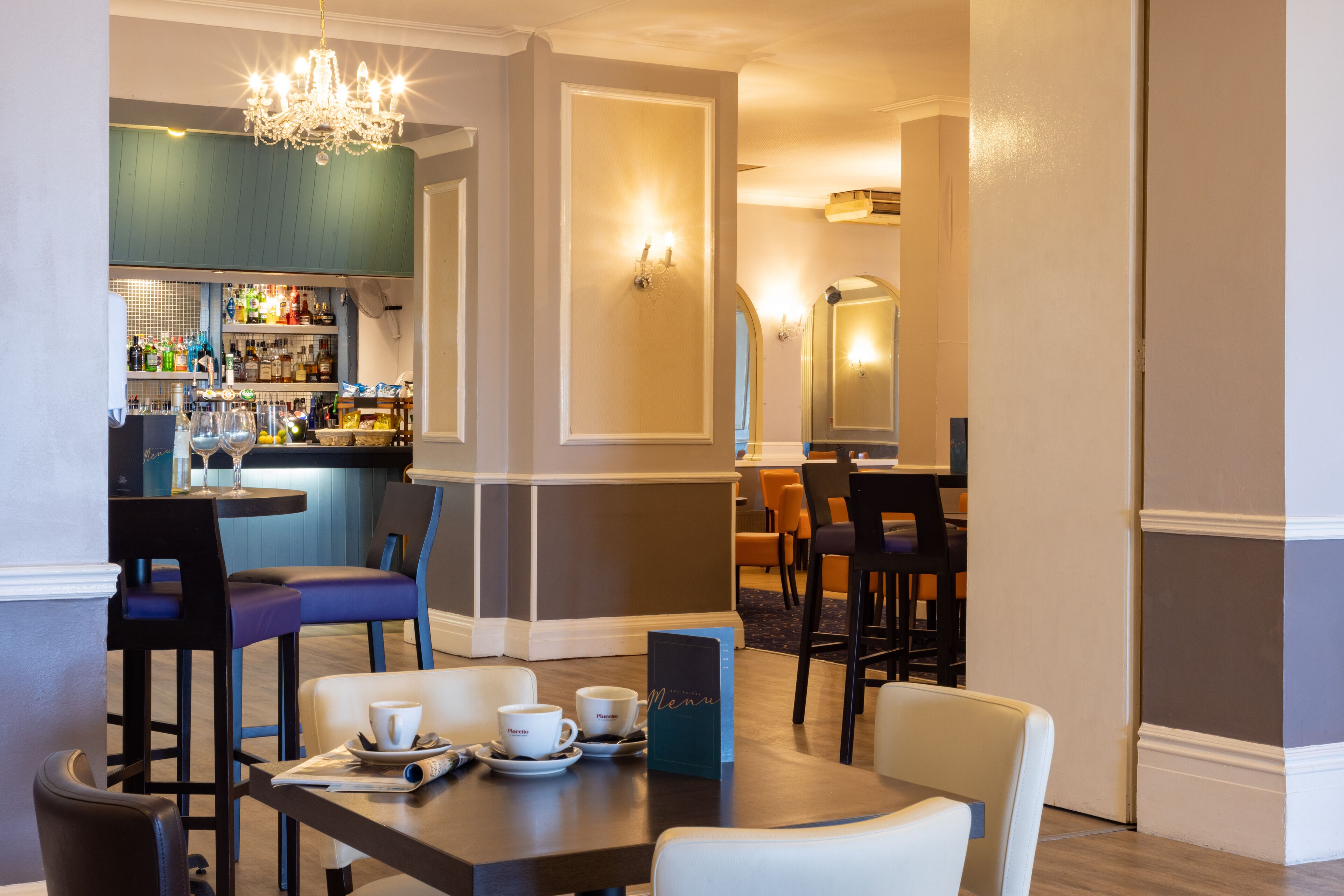 A hotel dining area with a bar, seating arrangements, and a menu stand.
