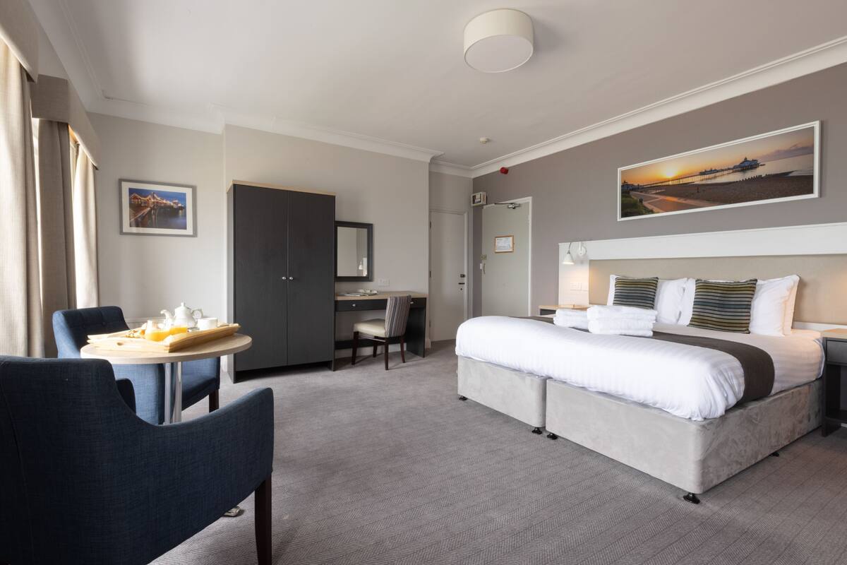 A hotel room with a bed, a desk, a chair, and a dining table.