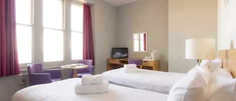 A hotel room with two beds, a desk with a computer, a chair, and a TV.