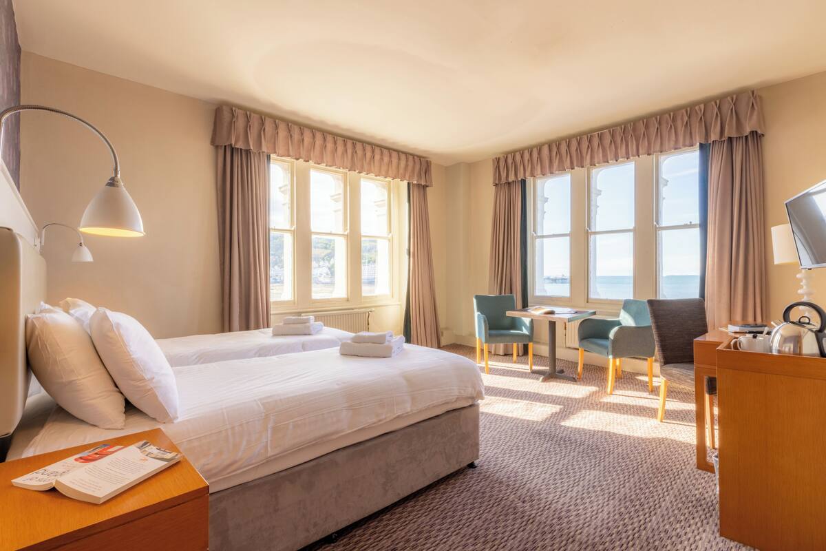 A hotel room with a large bed, two chairs, a desk, and a view of the outdoors.