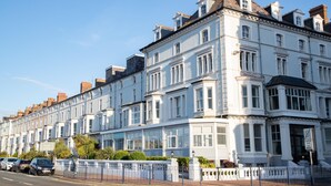 A row of white terraced houses with bay windows and a sign indicating a marine hotel. - The Marine Hotel (Llandudno)