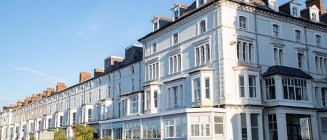 A row of white terraced houses with bay windows and a sign indicating a marine hotel.
