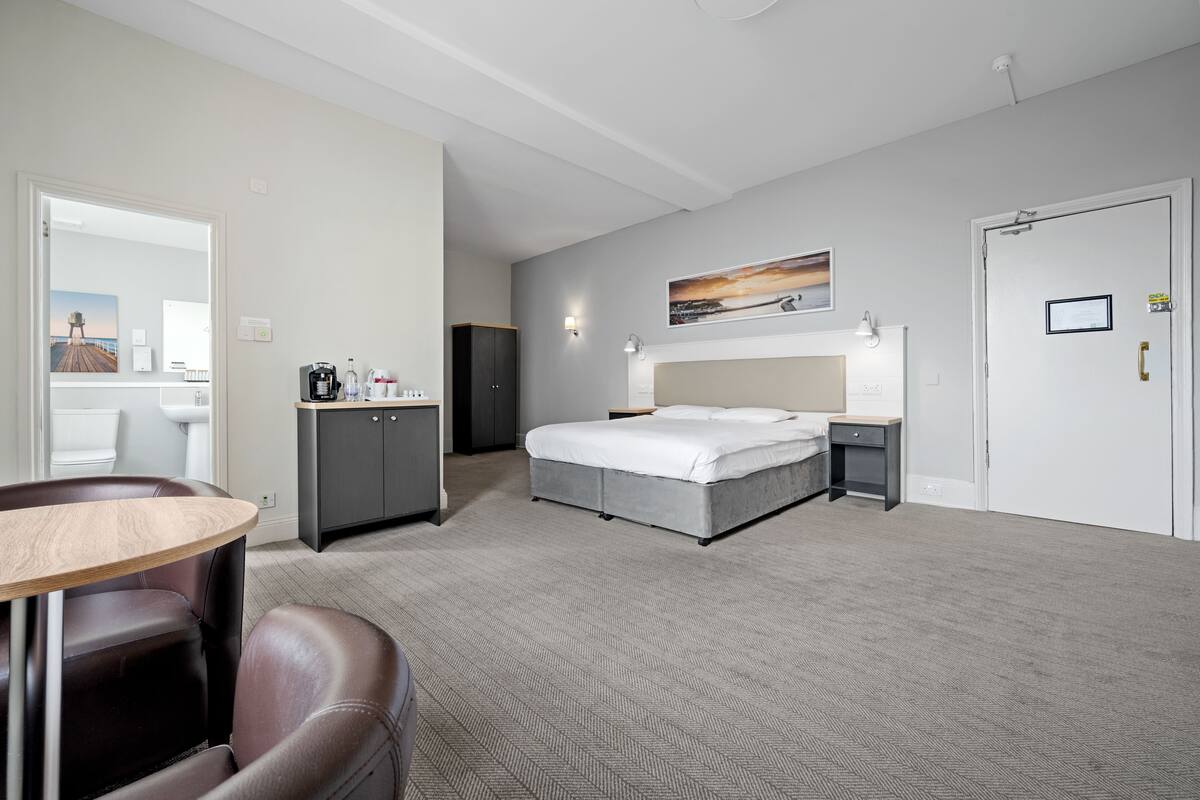 A hotel room with a bed, bedside table, and a desk with a chair.