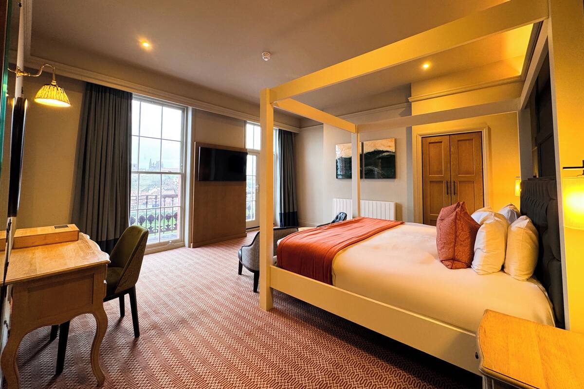 A hotel room with a large bed, a desk, a chair, and a television.