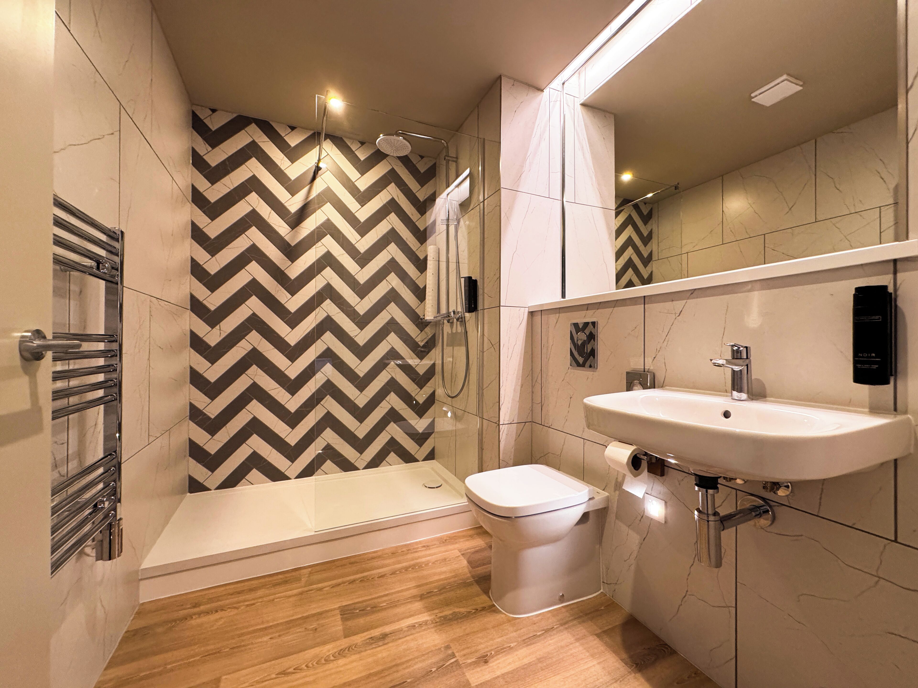 A modern bathroom with a shower, toilet, and sink.