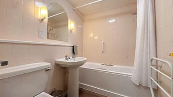 Un baño con lavamanos, espejo, ducha e inodoro.
