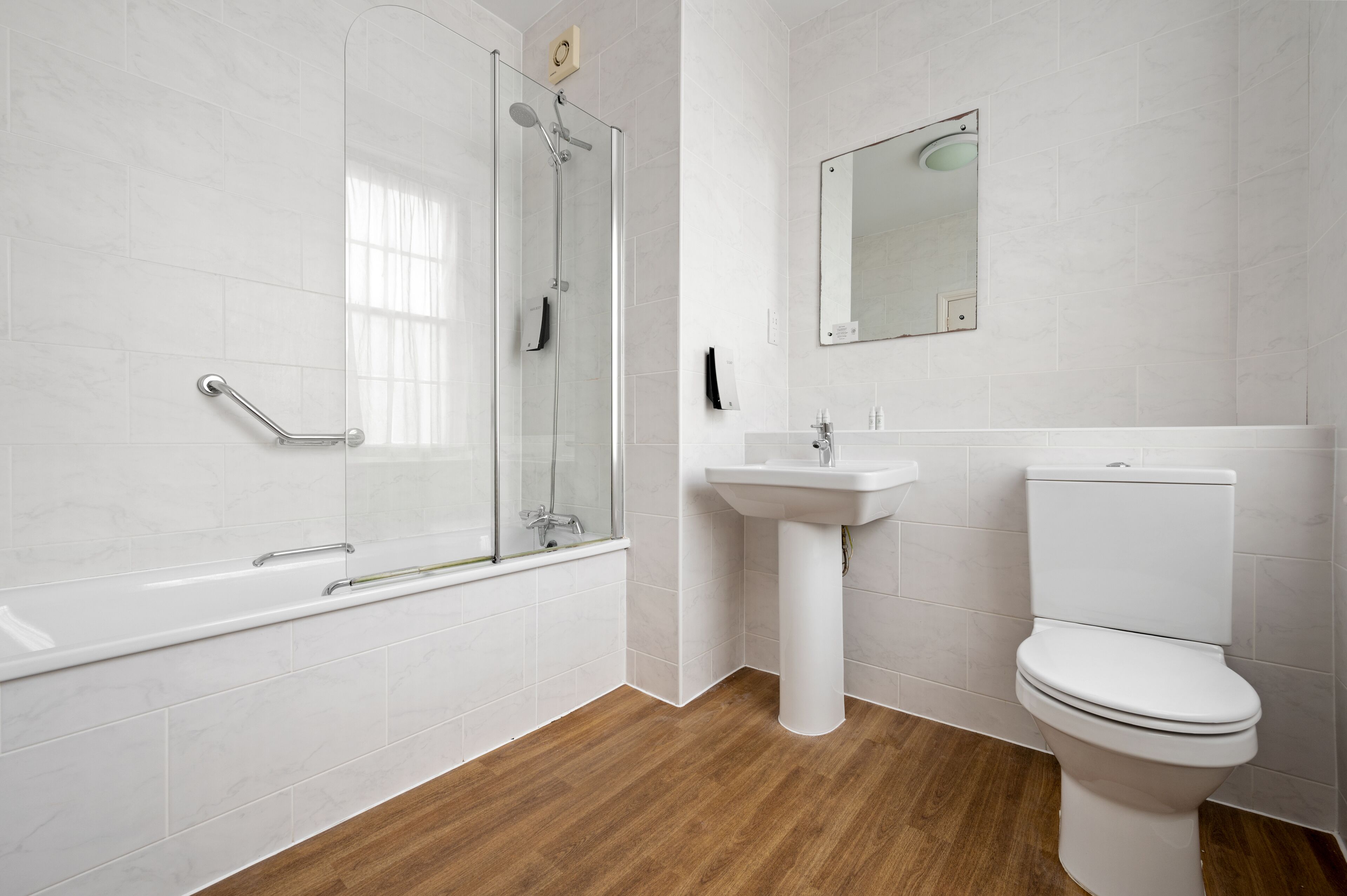 A modern bathroom with a glass shower enclosure, a pedestal sink, and a toilet.