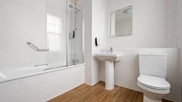 A modern bathroom with a glass shower enclosure, a pedestal sink, and a toilet.