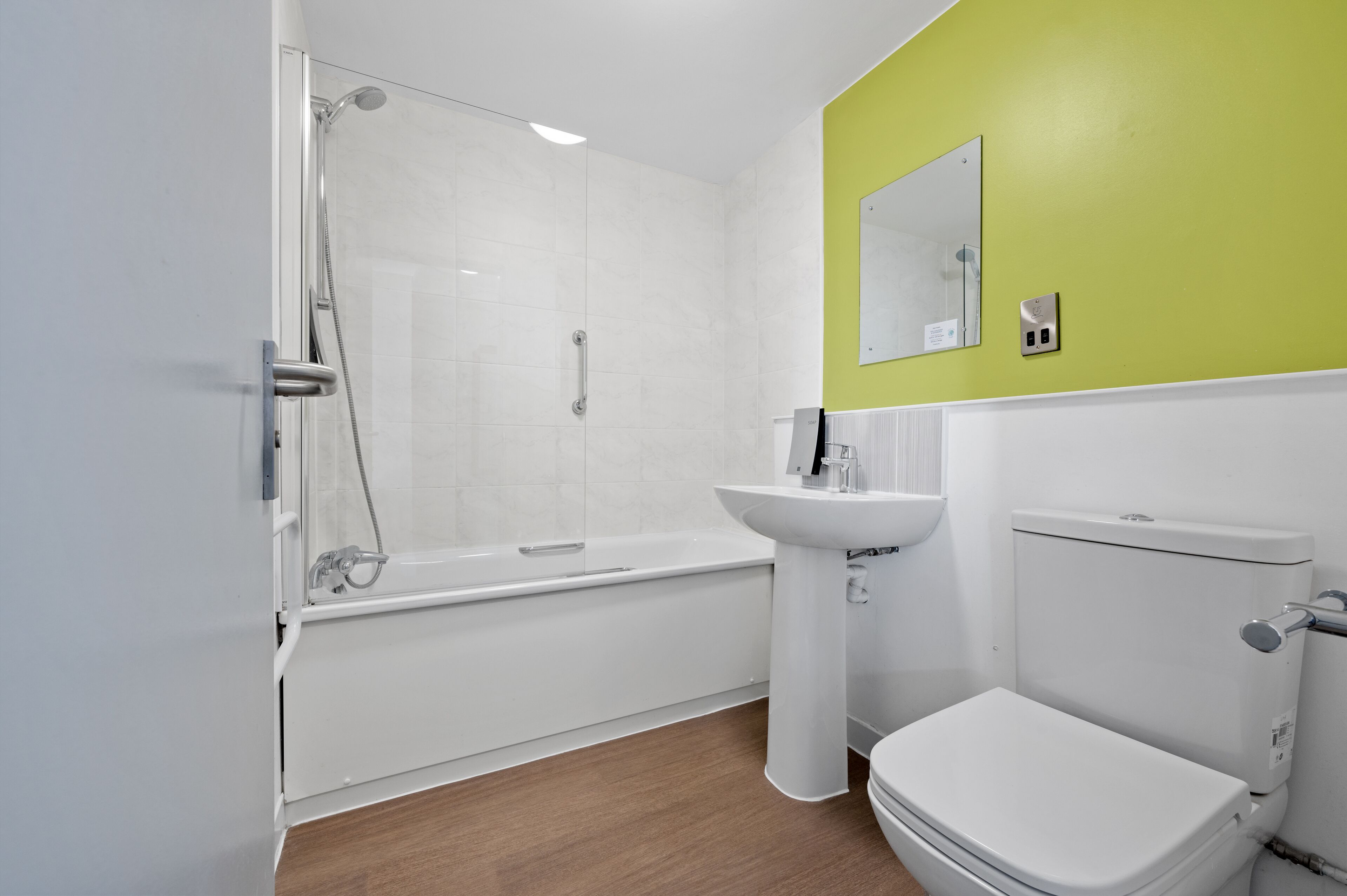 Un baño moderno con ducha de vidrio, un lavamanos blanco y un inodoro.