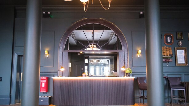 A reception area with a central counter, two columns, and a chandelier.