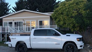 A white pickup truck parked in front of a house with a covered porch and a large tree to the right. - Right by the lake and fast walk to the beach.  (Saint Charles)