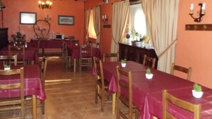 A dining area with tables covered in red tablecloths, wooden chairs, and a chandelier. - Rural house with garden and beautiful views (Sopuerta)