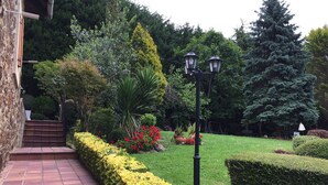 A garden with a paved pathway leading to a building entrance, surrounded by various plants and trees. - Rural house with garden and beautiful views (Sopuerta)