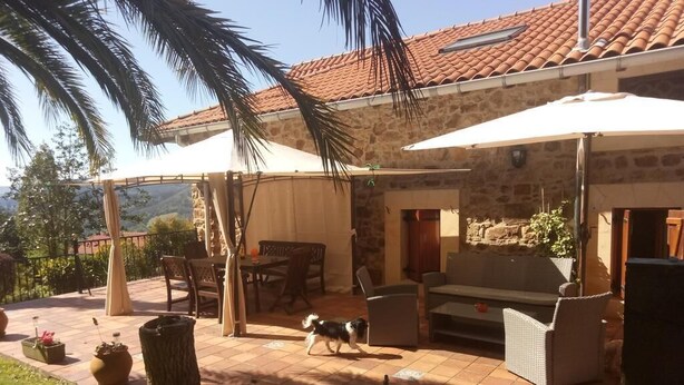 A patio area with outdoor furniture, a dog, and potted plants. - Rural house with garden and beautiful views (Sopuerta)