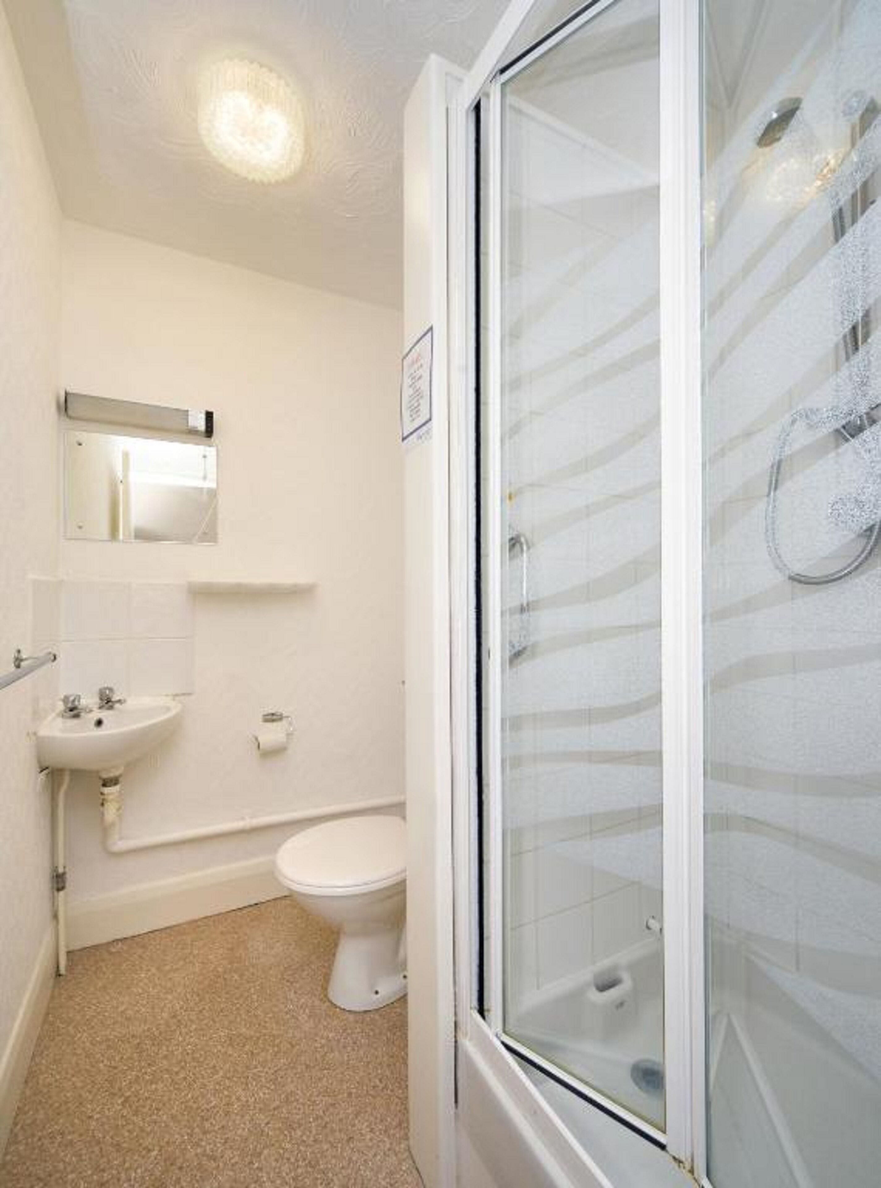A small, clean bathroom with a toilet, sink, and shower.