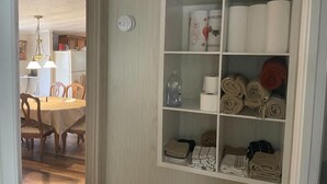 Ein Zimmer mit Essbereich, ein weißes Schränkchen mit Regalen für Handtücher und Pflegeprodukte.