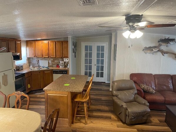A compact kitchen with wooden cabinets, a dining table, and a brown leather sofa. - Comfortable Okeechobee Home Minutes From Scott Driver, Okee-Tantie Boat Ramp (Okeechobee)