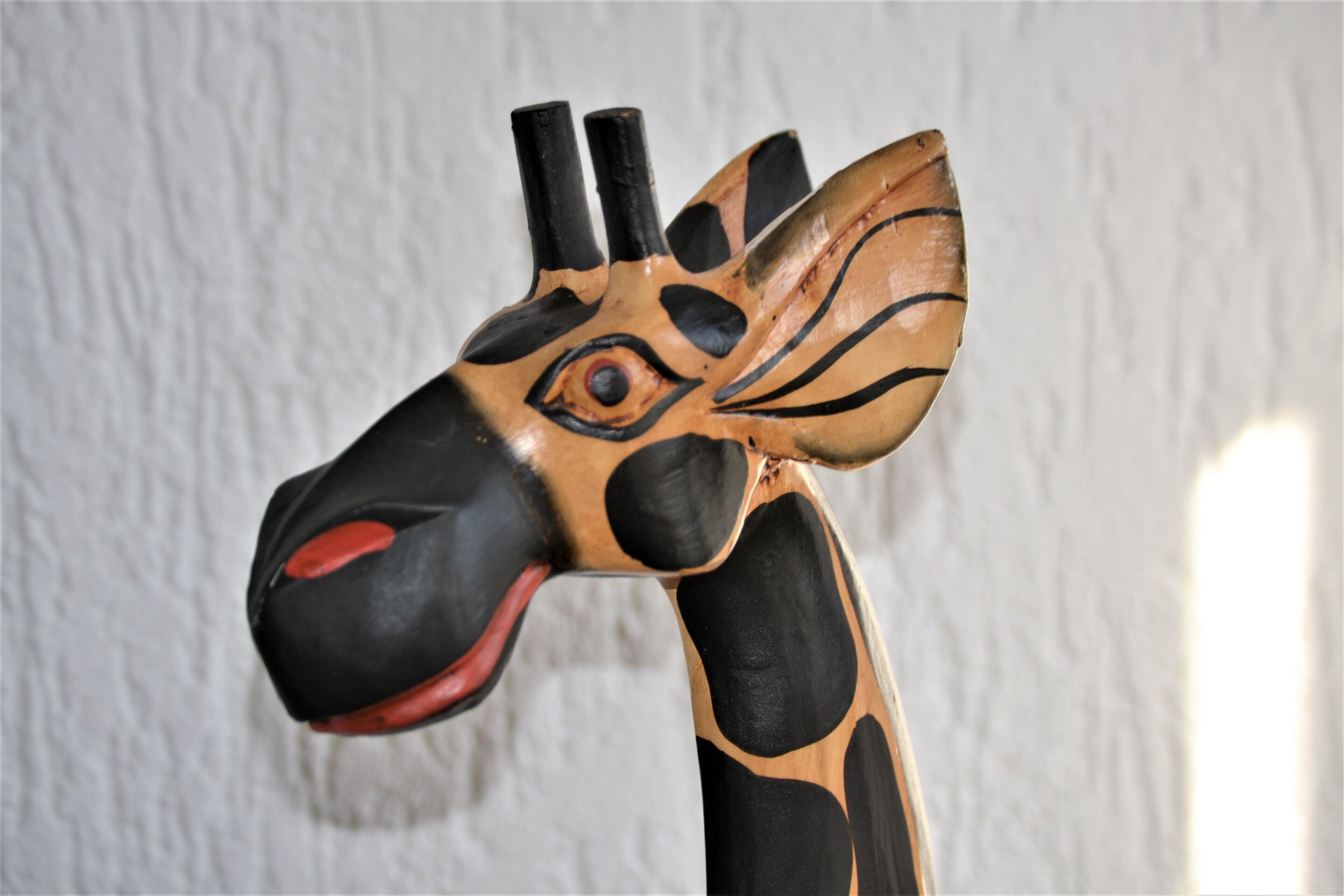 Eine Holzskulptur eines Giraffen mit schwarzem und beigem Muster.