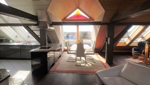 A modern loft with a kitchen, dining area, and seating space. - Penthouse Himmelreich spacious 155 m² maisonette with fireplace & air conditioning (Senftenberg)