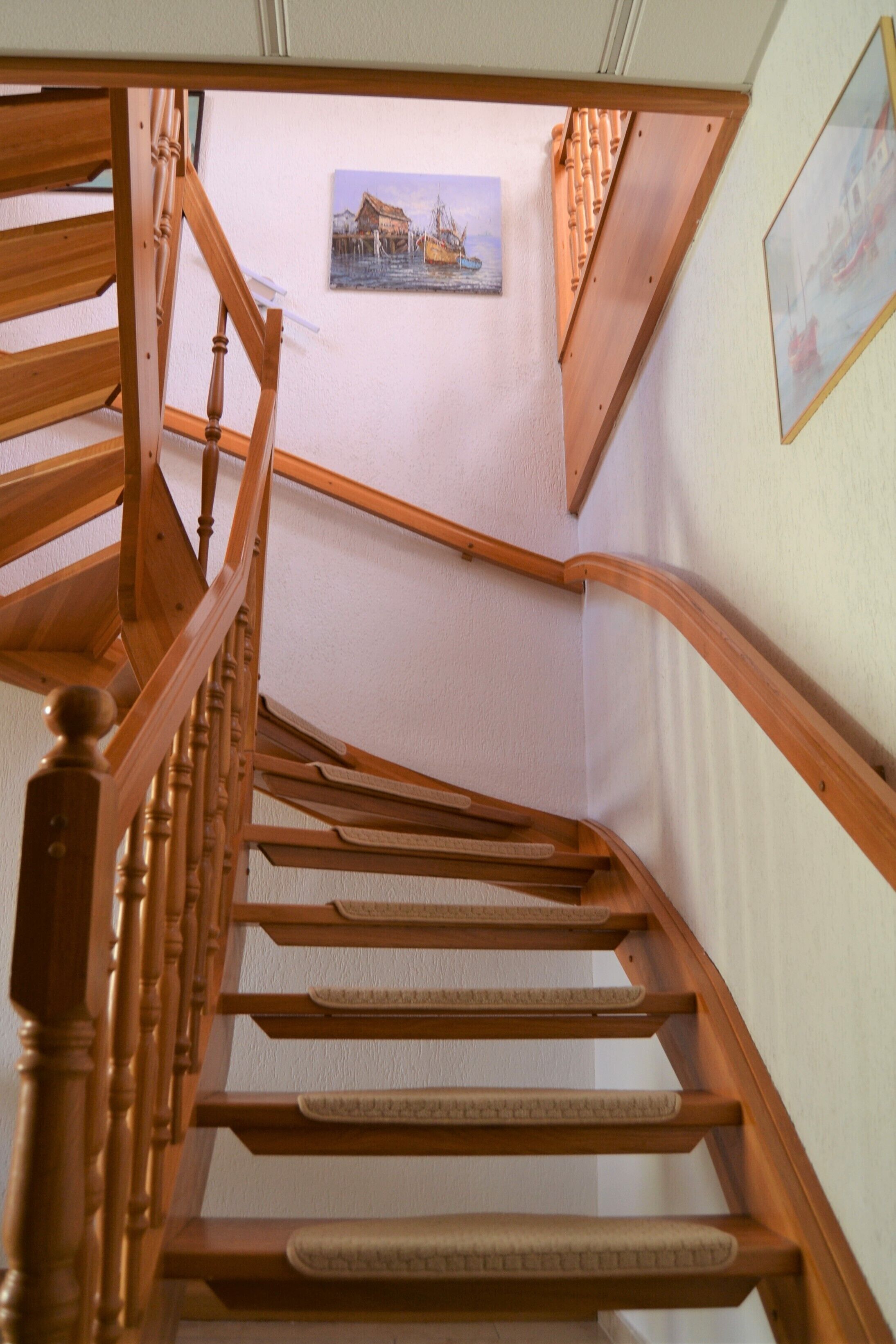 A wooden staircase with a handrail and a picture on the wall.