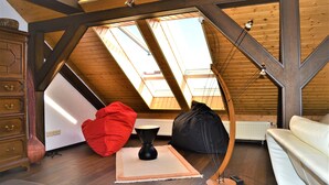 A loft-style room with a sloped ceiling, wooden beams, and skylights. - Penthouse Himmelreich spacious 155 m² maisonette with fireplace & air conditioning (Senftenberg)