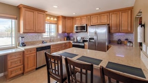 A modern kitchen with wooden cabinets, stainless steel appliances, and a granite countertop.