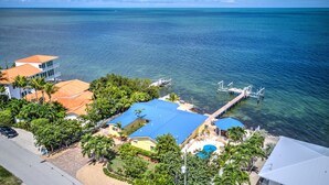 A coastal property with a swimming pool, a dock, and a clear view of the ocean.