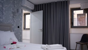 Et hotelværelse med seng, stol, et vindue med gardiner og en dør.