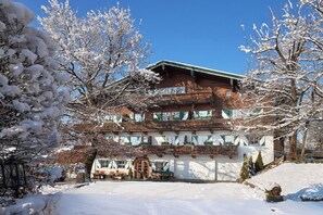 A multi-story building with a snow-covered landscape, a visible garage, and a clear sky.