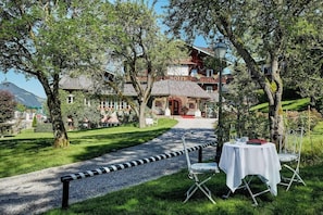 Ein Hotel mit traditioneller Chaletbauweise, einem Kiesweg, der zum Eingang führt, und Sitzgelegenheiten im Freien mit Tisch und Stühlen.
