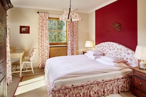 Ein Schlafzimmer mit einem Bett, einem Schreibtisch, einem Stuhl und einem Fenster mit Vorhängen.