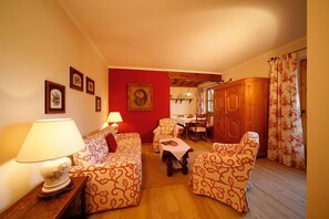Ein gemütliches Wohnzimmer mit einer Couch, Sesseln, einem Tisch und einem Holzschrank.