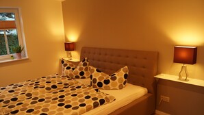 A bedroom with a bed, two bedside tables, and a window with blinds. - Gute Laune Hof Klingenthal (Klingenthal)