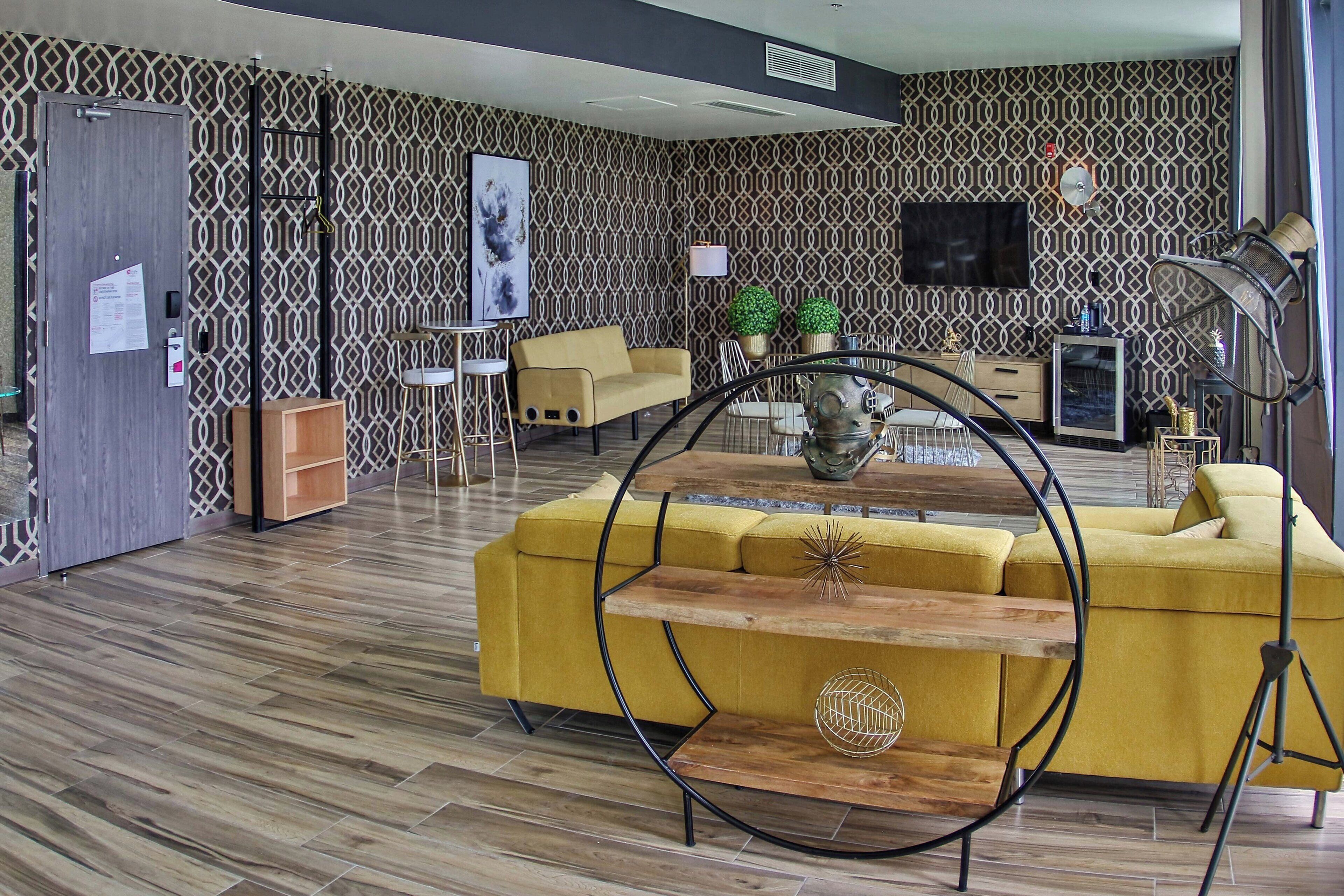 Una sala de estar moderna con un sofá amarillo, una mesa de centro de madera y un televisor en la pared.