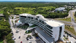 A modern hotel with a curved facade, multiple floors, and a parking area.